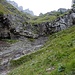 Der lang ersehnte Durchstieg genau in der Bildmitte durch das Felsband. Rechts vom Wasserfall kann diese Stelle einfach im Steilgras erklimmt werden. Wasserfall aufgrund der Feuchtigkeit eine III