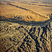 Unten die Mondlandschaft, oben die Namib Sandwüste. Der Sand, der von der Namib Wüste in Richtung Mondlandschaft geweht wird, fällt erstmal in den trennenden und meist trockenen Kuiseb Canyon, wo er einmal im Jahr vom Kuiseb River in den Atlantik getragen wird. So bleibt die Mondlandschaft Mondlandschaft.