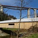 Die gedeckte Holzbrücke über die Urnäsch. Darüber baut sich mächtig der Sitter-Viadukt der Bodensee-Toggenburg-Bahn auf