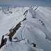 Unterwegs mit Skier auf einem Grat; die drei linken bez. Gipfel sind ebenfalls auf Skitour erreichbaar.