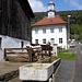 Ein Esel (mit entsprechender Wortmeldung) und zwei Pferde. Dahinter das Dorfschulhaus mit Glockenturm.