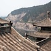 Blick über die Dächer des Xiangshan-Tempels auf das Westufer des Yi-Flusses mit den hunderten von Grotten.