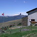 Zwischen der Schweizer und der Tessiner Fahne bei der Capanna Monte Bar sieht man den Monte Rosa
