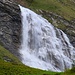 Ein eindrüchlicher Wasserfall vom Ri di Mutarasc gergiesst sich zur Alpebene Trachee herunter.