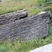 Un blocco di pietra con evidenti stratificazioni da cui ricavare lastre per le piode per i tetti o, come nella foto precedente, per realizzare protezioni sui sentieri.