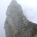 Selbst im Nebel eine eindrückliche Felsnadel, der [peak2053 Girenspitz], 2099m.
 Rechts der schmale Grat; mittig die T5-Passage und zu guter Letzt die paar Meter Kletterfelsen (II).