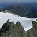 Blick vom Gipfel über den NW-Grat hinunter zum Glacier und Lac de Moiry: links die Zipfelmütze, darunter eine absteigende Seilschaft und die beiden Türme, die rechts umgangen werden können, am Horizont das Wildhorn