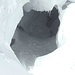 Ich schaue in dieses Loch, das sich als Eishöhle entpuppt hat und in das eine Fußspur hineinführt.