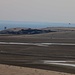 Tag 2 (25.12.):<br /><br />Sicht im äussertsen Südosten Qatars im Zoom der Küste entlang bis über die Grenze zu dem Hügeln in Saudi-Arabien am Horizont. Davor ist in der Bildmitte das Tor zum Inlandsee خور العديد (Khawr al ‘Udayd) zu sehen. Leider war mir der Aufpreis von 600 Qatar-Riyal (zirka 160.- sFr.) zu teuer für den zweistündigen Zusatzausflug, denn die Landschaftsformen sind nicht viel anders als während meines langen Spaziergangs hier der Küste entlang.