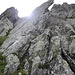 Un passaggio difficile (roccia in alto a sinistra) provo inizialmente ad aggirarlo sul suo retro (piccola linguetta erbosa che risale nel diedro in alto a sinistra), ma il bagnato mi fa desistere. Aggiro ancora di più per passare tutto a destra nella foto, meglio appigliato