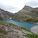 Lago dei Cavagnöö - in der Folge steigen wir von der Staumauer nach links über die Steinfelder bis zur Grenzen von hellgrauen und rotem Gestein, bevor die Querung nach rechts beginnt