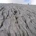 Karrenbildung - der Mineralienaltas aus dem Studium bietet Hilfe:<br />Karren - Karren sind Lösungsformen von Gesteinen, insbesondere Kalk und Gips, die durch chemische Auflösung entstehen. Sie sind typisch für Karstgebiete, treten sowohl in Höhlen als auch an der Oberfläche auf.<br />Karren entstehen durch Unebenheiten der Oberfläche, denen das abfließende Wasser folgt. Dabei wird Kalk gelöst, so daß eine winzige Vertiefung verstärkt wird, sich eine rinnenartige Struktur bildet in der auch weiterhin Wasser abfließt. Karren treten dabei in den verschiedensten Größen auf, von kleinen Rinnen bis hin zu großen Spalten.