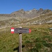 Der Gipfel links vom Monte Gavia ist der Vorgipfel. Direkt vor dem Monte Gavia ist der weitere Vorgipfel, der den Monte Gavia nahezu verdeckt. Der Anstieg verläuft auf der Geländeterasse in der Mitte des Bildes zum linken Bildrand und dann über den anfangs grünen Rücken immer am Grat entlang zum Gipfel. 
