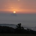 Sonnenaufgang, kurz unterhalb der Sonne dringt die Abdampfwolke eines nordböhmischen Kraftwerkes durch die Nebeldecke