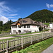 Unterwegs in Zell-Pfarre / Sele-Cerkev - Es geht direkt an der Schule vorbei. Über eine kleine Brücke am Wegweiser (im Rücken des Fotografen) geht's "hinter den Zaun".