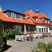 Allinge-Sandvig - Blick zum ehemaligen Bahnhofsgebäude aus dem früheren Bereich der Gleise. Von 1913 - 1953 befand sich hier die Endstation der [https://da.wikipedia.org/wiki/Allingebanen Allingebanen],  Rønne - Allinge-Sandvig, heute gibt es hier die schön hergerichtete Pension Langebjerg.