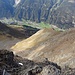 Blick hinab ins Stanzertal. Links der Bildmitte erkennt man deutlich die Haarnadelkurve auf der Forststraße und, mit einiger Anstrengung, eine Schneise, die in Richtung Kar leitet, ohne direkt hineinzuführen. Sie zweigt von der Forststraße ab kurz bevor diese hinter der Geländewölbung verschwindet.