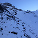 Auf einer angedeuteten Pfadspur über den nur dünn verschneiten Geröllrücken: darüber das Couloir zum Gamchi-Schafberg und links oben die Flühe des oberen Dürrebergs