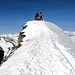 <b>Il tratto più pericoloso dell’escursione è proprio l’aerea crestina che conduce sulla cima, lungo la quale sostano due alpinisti intenti ad osservare il Biancograt del Bernina. </b>