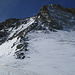 Aufstieg über wechselhaften Schnee zur oberen felsigen Hälfte des Pointe de Zinal NE-Grats: gut sichtbar die Schneerinnen im unteren Teil und der markante Gendarm rechts davon