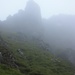 Der Weg führt um die Felsspitze links herum. Ich glaube oder vermute, dass der Ben Arthur rechts hinten im Nebel steht.
