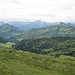 Blick nach Südosten. Unten halb verdeckt liegt Damüls, die Häuser am Hang gehören auch dazu. Der dreieckige Berg rechts ist das Glatthorn, und ganz hinten sieht man die richtig hohen Berge des Alpenhauptkamms. 