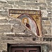 L'affresco più antico racchiuso da una lunetta, è posto sopra la porta che conduce in chiesa e rappresenta San Benedetto benedicente. L'opera frammentaria palesa delle affinità con gli affreschi absidali e può quindi essere datata ai primi decenni del XIII secolo.