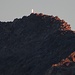Das im Sonnenlicht glänzende Gipfelkreuz des Almagellerhorns herangezoomt 
