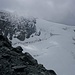 Am Col des Roches öffnet sich der Blick auf den weiteren Aufstieg über den Glacier du Geay. Nicht sichtbar ist der steile, felsige Abstieg zum Glacier du Geay. Der Glacier du Geay, über den auch der Normalweg vom Refuge du Mont Pourri verläuft, kommt von rechts unten hoch. Der Schlussgrat zum Gipfel zieht über den markanten Schneegrat nach links oben in die Wolken. Links oben der Nordgrat, über den auch regelmäßig der Abstieg vom Mont Pourri erfolgt.