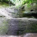 Am Wildschützensteig. Zunächst geht es auf ein paar Holzstufen zu einer Felswand, die mit Hilfe eines quer verlaufenden Bandes und eines Geländers erstiegen wird. 