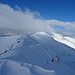 Der Gipfelgrat ist tief verschneit und teilweise verwechtet, im Hintergrund in den Wollken ist der Hochrettenstein.