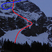 Stieregrat N-Flanke vom Zustieg über die Geissalp mit der Aufstiegs- und unteren Abfahrtsroute (rot): unten die Einstiegsrampe, links darüber die untere Mulde und die Rippe, und oben das N-Couloir zum Grat, der nach rechts zum Gipfel führt. Die Abfahrtsvariante (blau) führt vom Gipfelgrat über die Schrägrampe, die obere Mulde und das obere Band zurück zum unteren N-Couloir