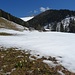 Vom Frühling in den Winter: Die ersten Schneeglöckchen vor der eingeschneiten Wiese unterhalb der Spitzenbergalm, im Hintergrund der Gipfelaufbau der Tannschwärze