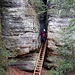  Zwei steile Metalltreppen führen durch den engen Spalt in einer senkrechten Felswand hinunter und schließlich hinaus in freieres Gelände.