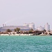Tag 4 (4.5.):<br /><br />Anfahrt auf die Insel الدار (Ad Dār) mit Zoomfoto. Die Bildperspektive täuscht, denn das Zementwerk des Aluminiumkombinats liegt weit hinter der Insel auf سترة (Sitrah) 