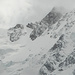 Zuunterst vom Abstiegsrücken nach der Alpe Roffelstafel werden zwischen den sich lichtenden Wolken Silbersattel, Grenzgipfel und Zumsteinspitze sichtbar, darunter der E-Flanke über dem Marinellicouloir