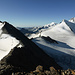 Blick vom Balfrin NW- zum Hauptgipfel: auf dem Verbindungsgrat liegen nur noch wenige Firnreste. In der Mitte der Riedpass, rechts darunter der Riedgletscher, darüber das Ulrichshorn, am Horizont von rechts u.a. Lensspitze, Mischabelgrat, Rimpfischhorn-, Allalin-, Strahl- und Fluchthorn, Monte Barone, Joderhorn und - links vom Egginer - das Spechhorn