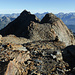 Typische Beschaffenheit des Verbindungsgrats, hier zwischen Gross Bigerhorn und Balfrinjoch: Geröll, Schutt, leichte Felsen und hie und da ein Steinmann. Hinten links das Schwarzhorn, am Horizont von links u.a. Wildstrubel, Rinderhorn, Altels, Balmhorn, Doldenhorn, Fründenhorn und Blüemlisalp