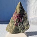 <b>Piropo Mg3Al2[SiO4]3 e Olivina (Mg,Fe)2SiO4 nella Peridotite - 5,7 cm - collezione personale.<br />L’Alpe Arami è noto a livello mondiale per la peridotite, una roccia eruttiva, scura, molto pesante di color verde a causa della presenza di olivina, che contiene dei granati rosso rubino, chiamati piropo. La prima concessione per l’estrazione risale addirittura al 1482. La notorietà del giacimento ha raggiunto l’apice dopo che il Corriere della Sera, nel 1996 pubblicò un articolo dal titolo “Misteriose rocce a Bellinzona! Con diamanti?”, a firma Bignami Luigi (giornalista scientifico). <br />Ogni cristallo è bordato da un anello più scuro; quest'ultimo è un orlo di reazione del cristallo stesso (chelifite), composto da un aggregato microcristallino di anfibolo e spinello.<br />Recentemente, un gruppo di ricercatori dell’Università della California (Riverside) ha ipotizzato che queste rocce dell’Alpe Arami sarebbero venute alla superficie da una profondità molto maggiore di quella sino ad oggi valutata, probabilmente intorno a 400-670 km, dalla zona di transizione tra il mantello esterno e quello interno. Il sito mineralogico dell’Alpe Arami rappresenta pertanto un’importante testimonianza della composizione mineralogica dell’interno del nostro pianeta e dei processi di subduzione legati alla formazione delle Alpi.</b><br />