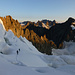 Aufstieg in einer guten Spur durch die von mächtigen Spalten durchzogene NNE-Flanke zur Brèche Lory, darüber bereits in der Morgensonne links Tour de Bonne Pierre, rechts der Roche Faurio, dazwischen von links u.a. Le Rateau, Pic Bourcet, La Grande Ruine, La Meije und der Pic Gaspard