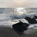 BlickBei Saline Joniche - Blick auf das Ionische Meer, das ein Gemisch aus Wellen und Gegenlicht an den Strand spült.