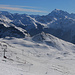 Aussicht bei der Bergstation „Vallatscha“ auf 2652m vom obersten Skilift auf das Skigebiet und dessen namengebender Gipfel Minschuns (2519m). Am Horizont in Italien steht der mächtige Ortler / Ortles (3905m).