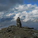 Gipfelsteinmann Chilchalphorn mit den wolkenumrahmten Gipfelzielen des nächsten und übernächsten Tages: Valserhorn, Bärenhorn, Piz Tomül und Tällihorn (von rechts nach links).