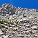 Rechts unterhalb der Gipfelmarkierung befindet sich der Kamin, der einen Ausstieg auf den Gipfelgrat erlaubt (erkennbar in der Vergrösserung durch den V-förmigen glatten Felsen mit waagerechtem Riss).
