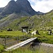 Eine kleine Brücke talabwärts der Alp Güglia führt über die Ova dal Vallun.<br />Der Piz Polaschin zieht die Blicke auf sich