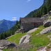 Da Trüsp, alle spalle della cascina, in alto sulla costa boschiva, si intuisce il ripiano dell'Alpe Pian Forno