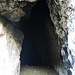 Man passiert eine kleine Höhle in der helbraunen Felsmauer.