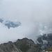 Blick vom Monte Daino nach Osten. Man sieht viel Brenta-Nebel, und in einer kleinen Lücke nahe des rechten Bergs ein Stück des Molveno-Sees.