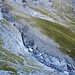 Man überquert auf einst vom Gletscher abgeschliffenem Fels einen Bachlauf und steigt auf einer Schotterrippe noch ein wenig bergauf. 