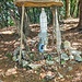 <b>Dopo alcune decine di metri sono costretto a spingere la bici e a zigzagare fra cespugli, rami e tronchi caduti. Alle 10:25 arrivo in vetta. È contrassegnata da una madonnina custodita in una “cappella” costituita di ramina verde, assai primitiva, un’arte naif per niente pregevole. È strano che ogni persona, ovviamente in buona fede, possa posare in luoghi pubblici ogni sorta di oracolo senza che le autorità competenti intervengano.</b>